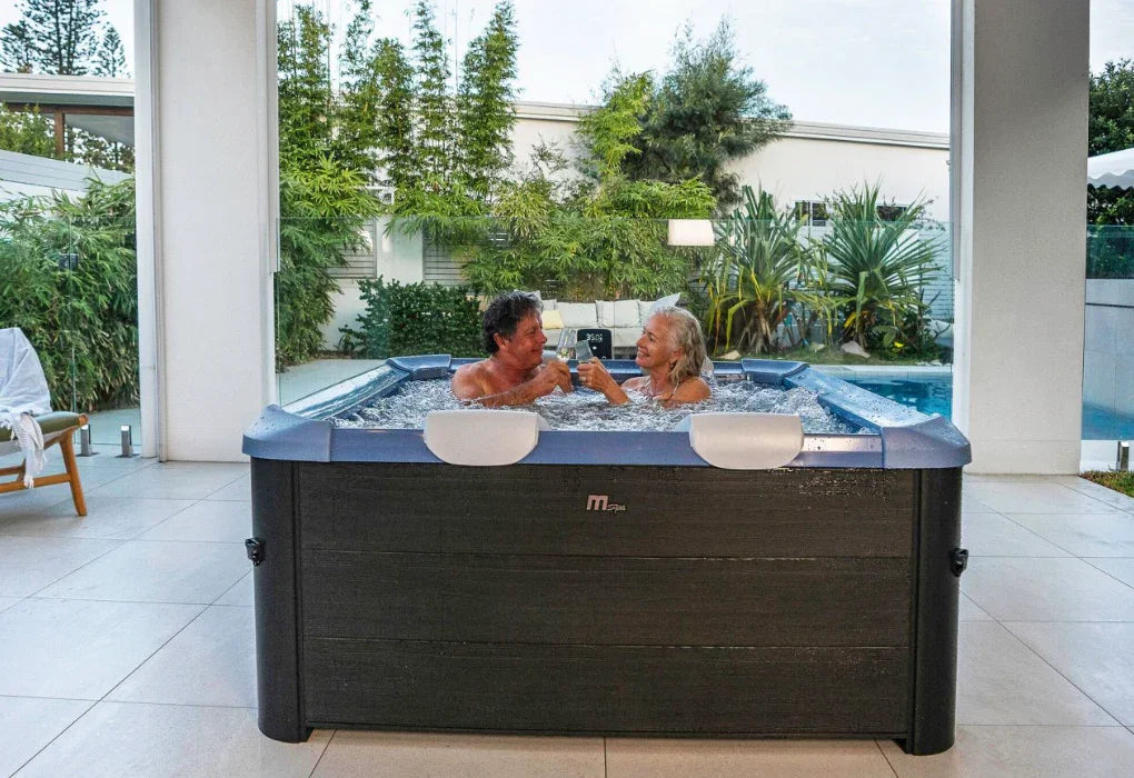 Bahçede mspa jakuzide keyif yapan yaşlı çift, suyun içinde içecekleriyle rahatlıyor