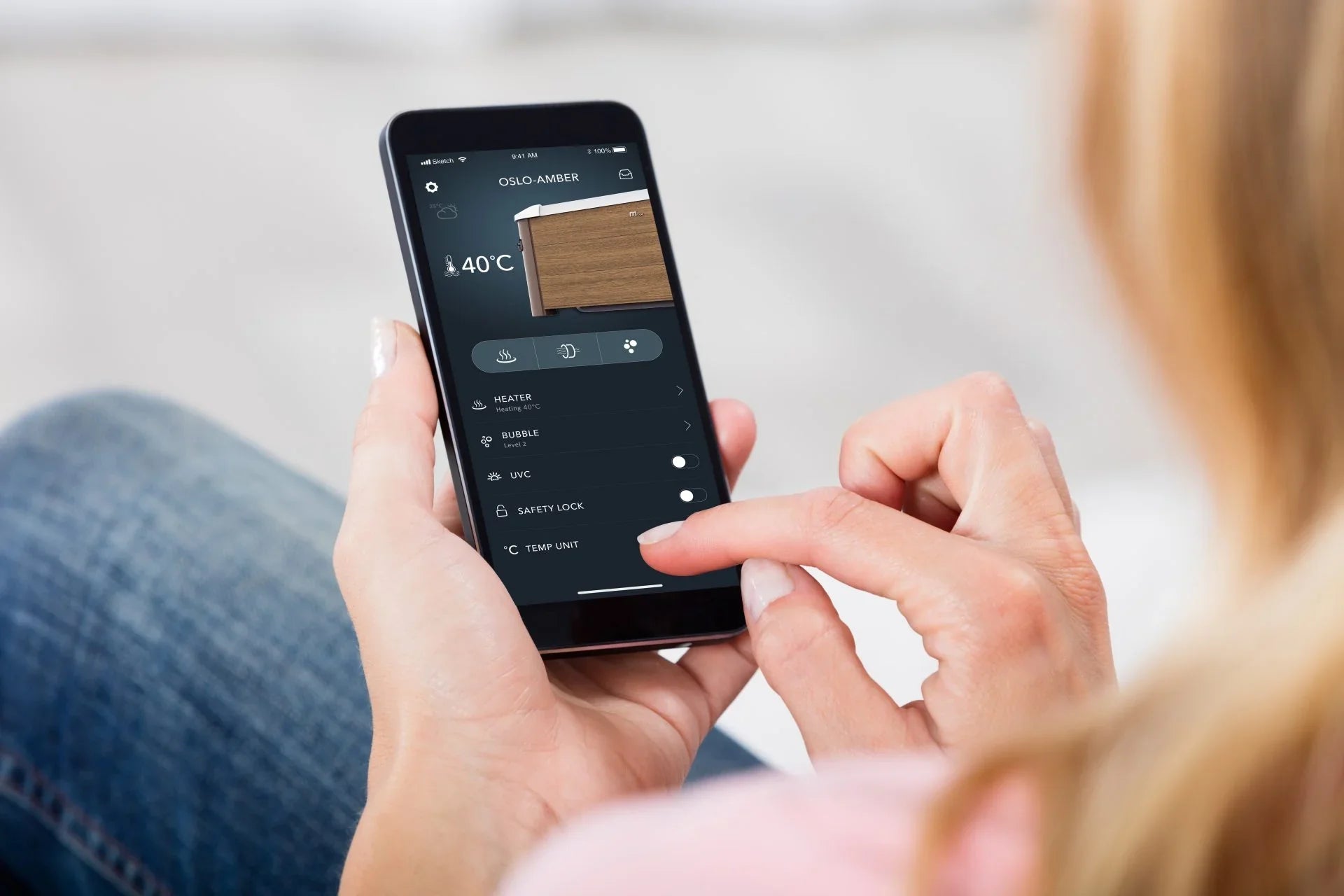 Kadın, OSLO-AMBER 40°C sıcaklık ayarı ile akıllı ısıtıcı kontrol uygulamasını telefonunda kullanıyor