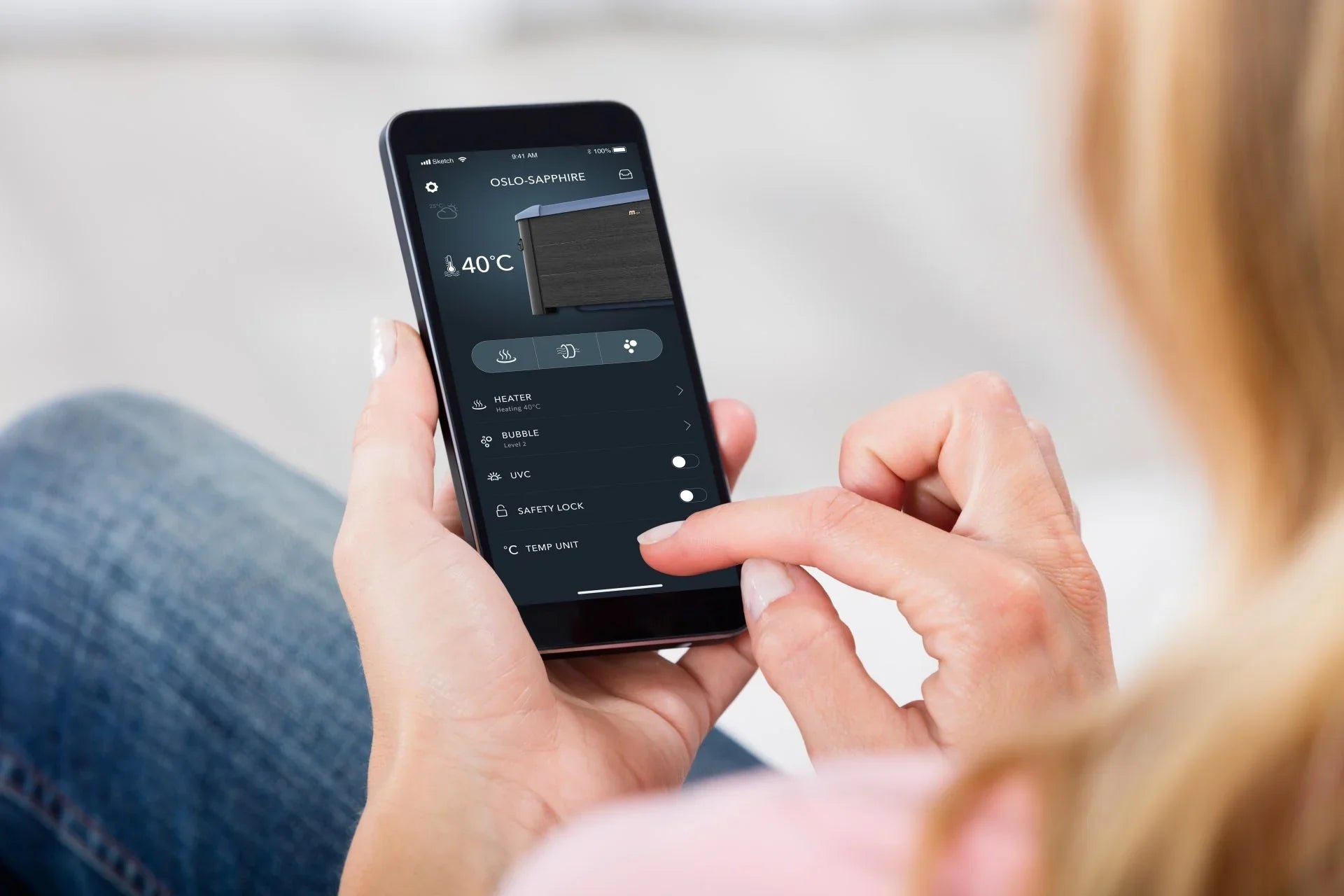 Kadın elinde Oslo Sapphire uygulamasında 40°C sıcaklık ve çeşitli kontrol seçenekleri olan akıllı telefon