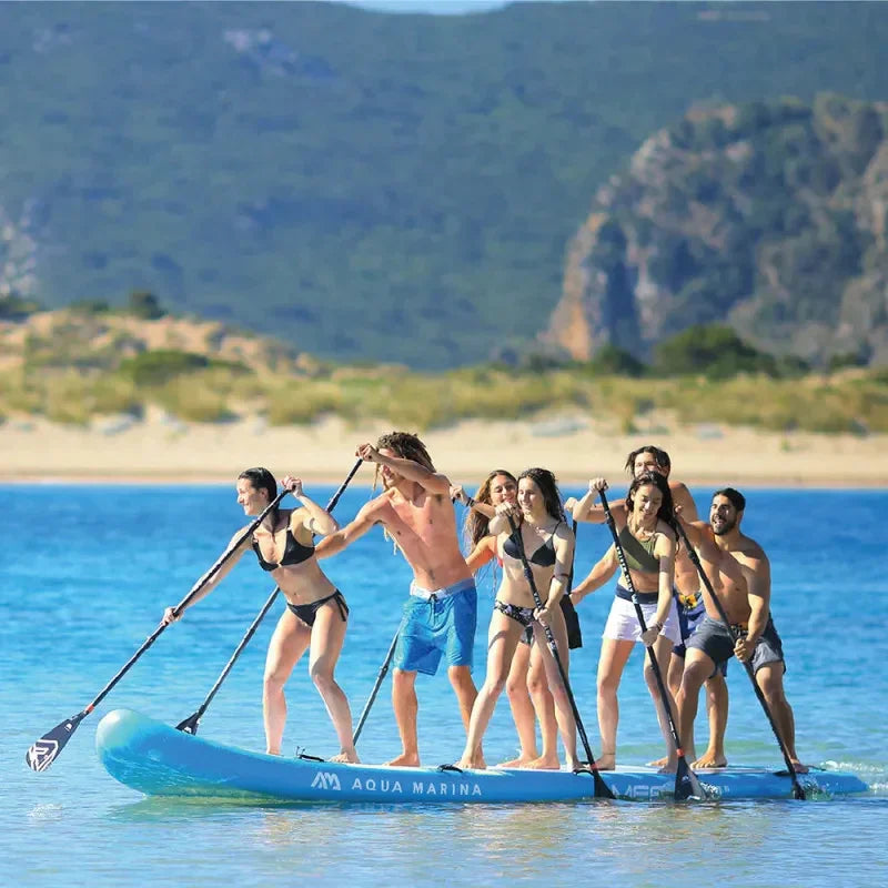Group of eight people paddleboarding together on a large blue Aqua Marina inflatable stand-up paddle board