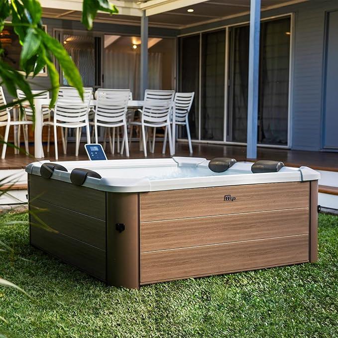 Bahçede ahşap panel dış yüzeyli, beyaz iç kısmı ve boyun yastıklı jakuzi