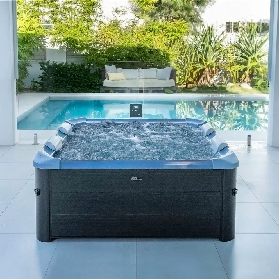 Büyük jakuzi ve arka planda havuz ile bahçede modern açık spa ortamı