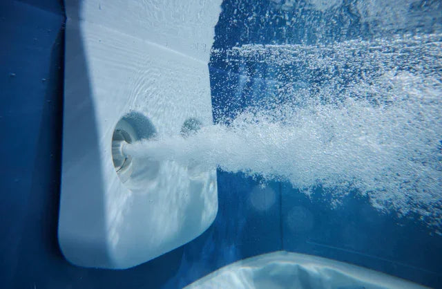 Mavi jakuzide su püskürten spa jeti ve köpüklü su akışı