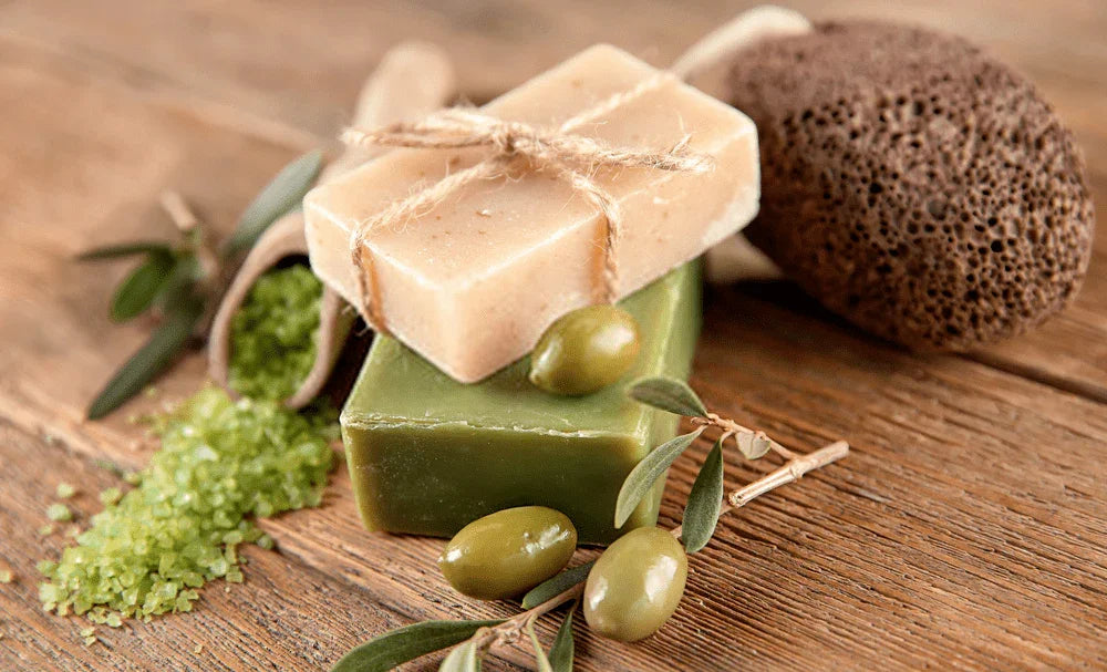 Doğal zeytin sabunu, zeytin dalı, yeşil banyo tuzu ve ponza taşı ahşap zeminde